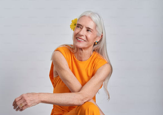 Woman with grey long hair in a beautiful orange dress with a smile
